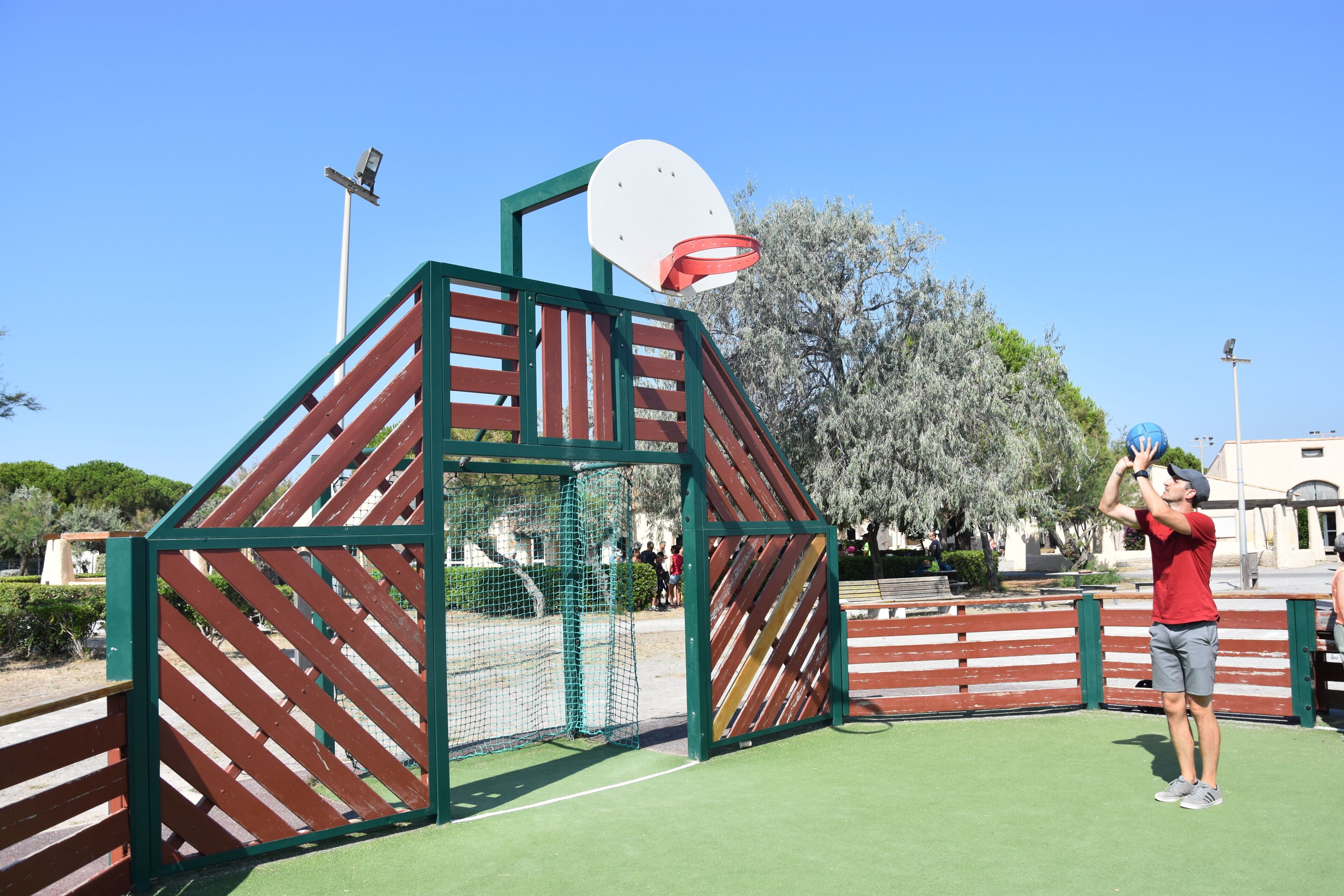 A basketball court with a wooden structure, a basketball hoop, and a clear blue sky.