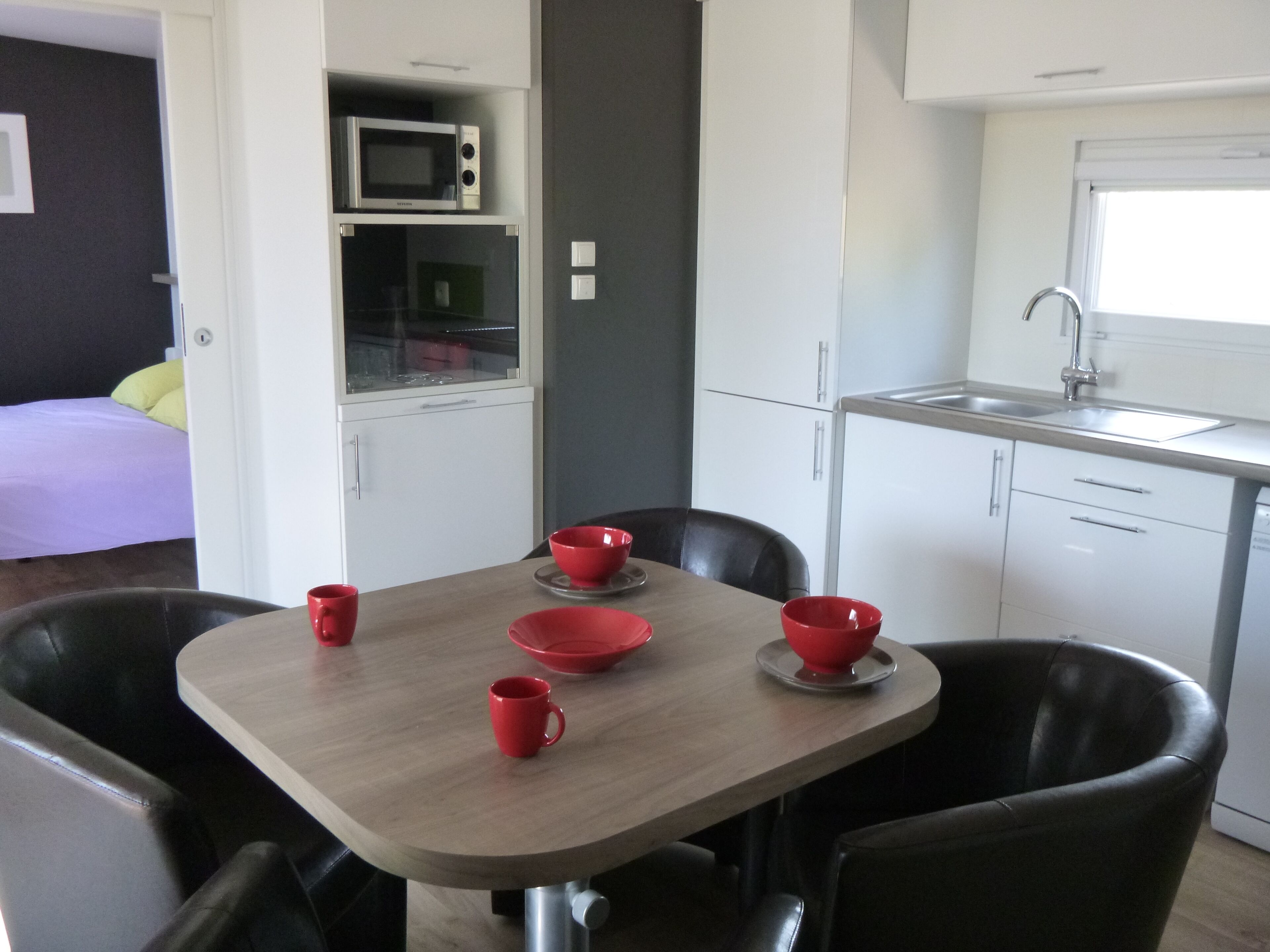Uma cozinha compacta com micro-ondas, pia e área de refeições com mesa e cadeiras.