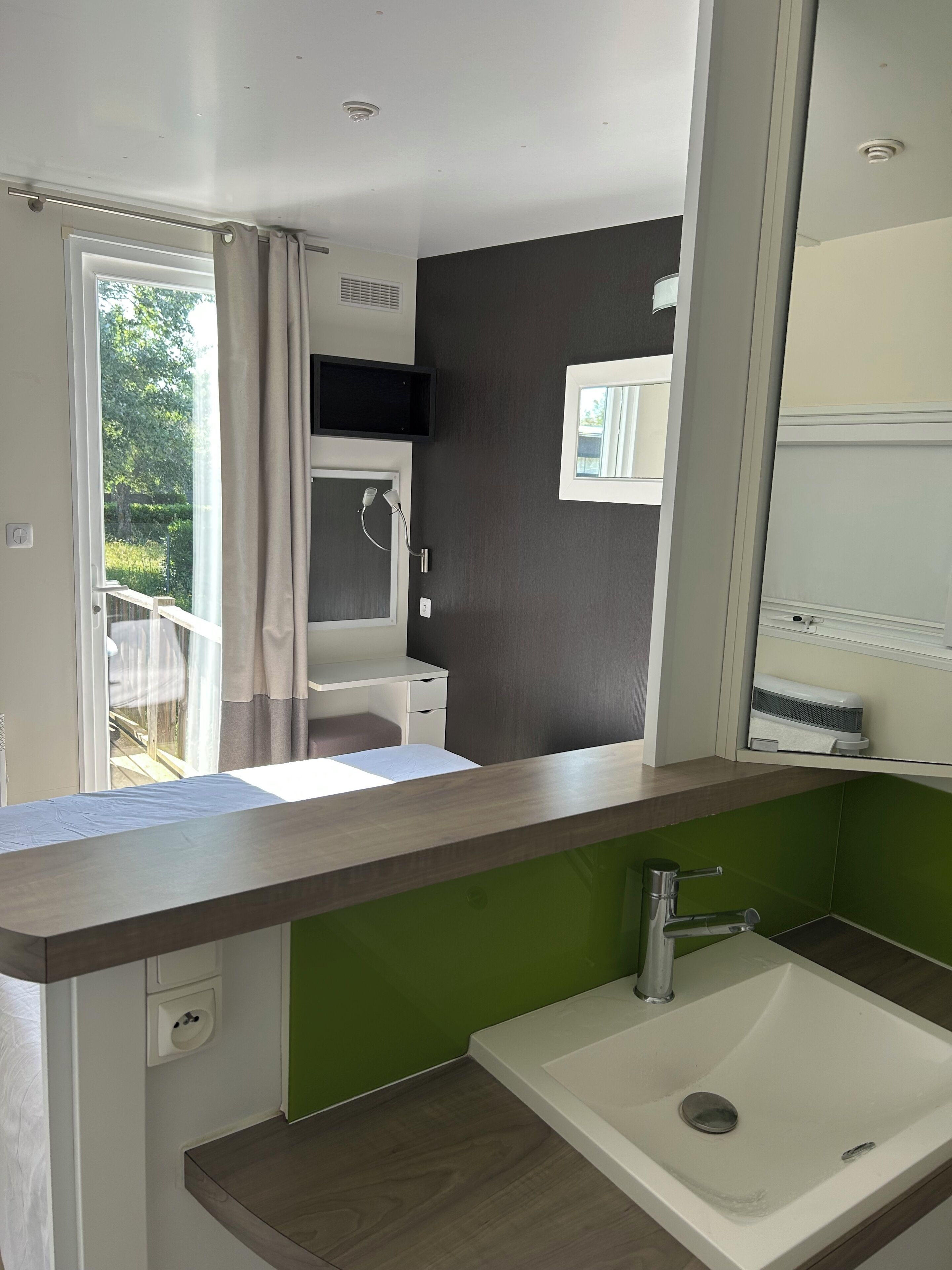 Un baño moderno con lavamanos, espejo y ducha.