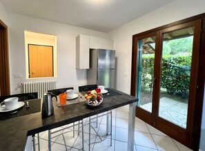 Una cocina moderna con comedor, refrigerador y vista a zonas verdes.