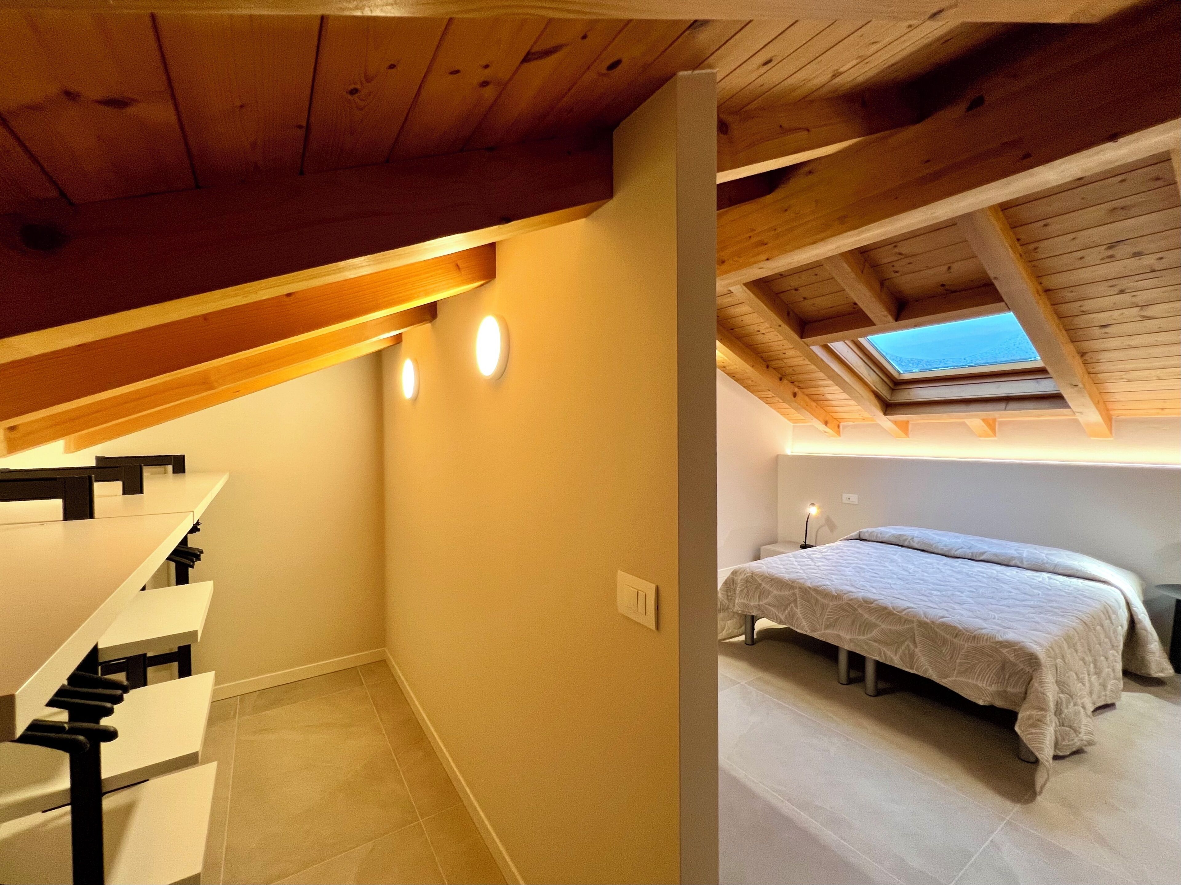 A bedroom with a skylight, a bed, and a staircase.