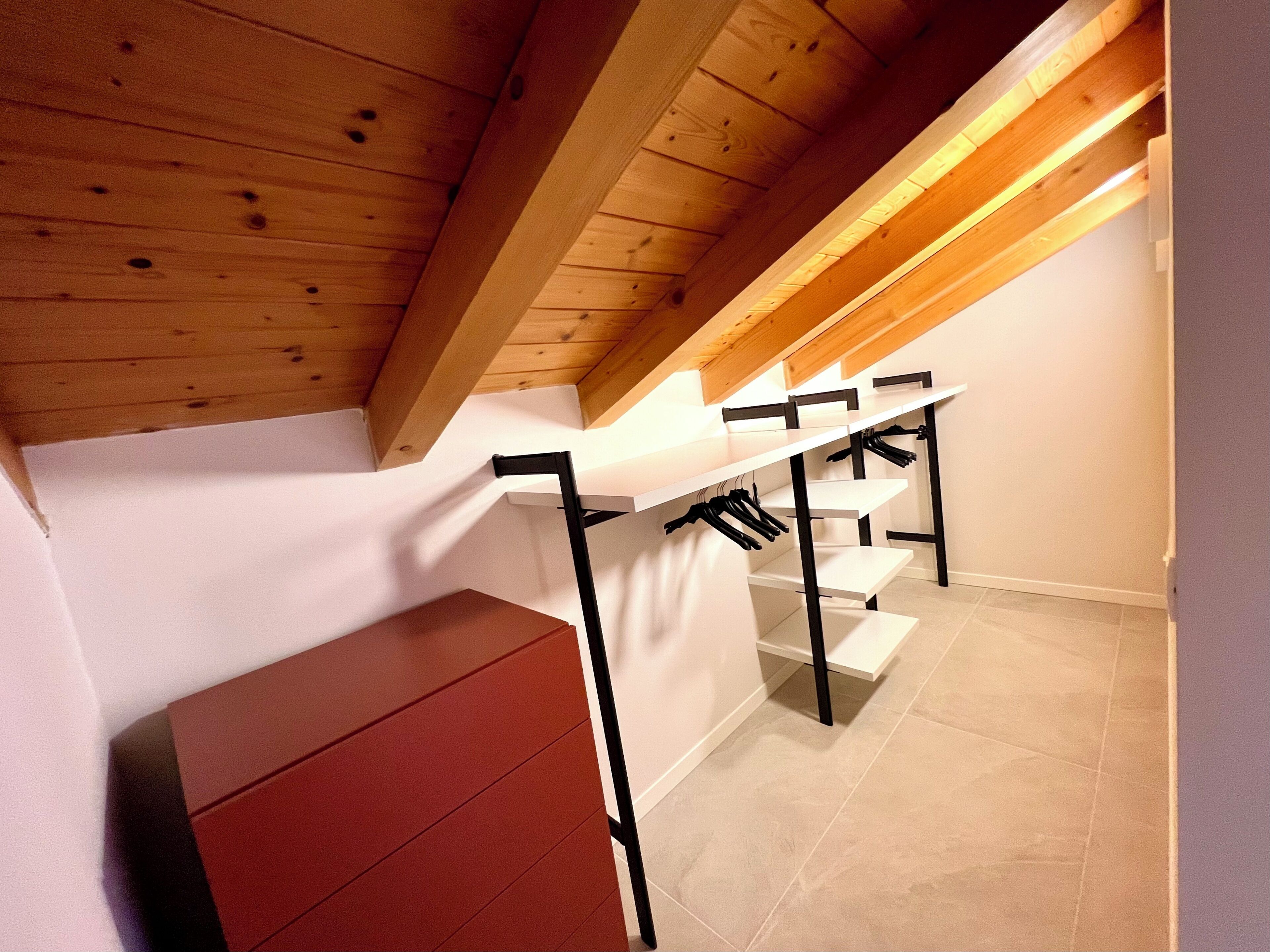 A wooden ceiling with exposed beams, a white wall, and a red cabinet.