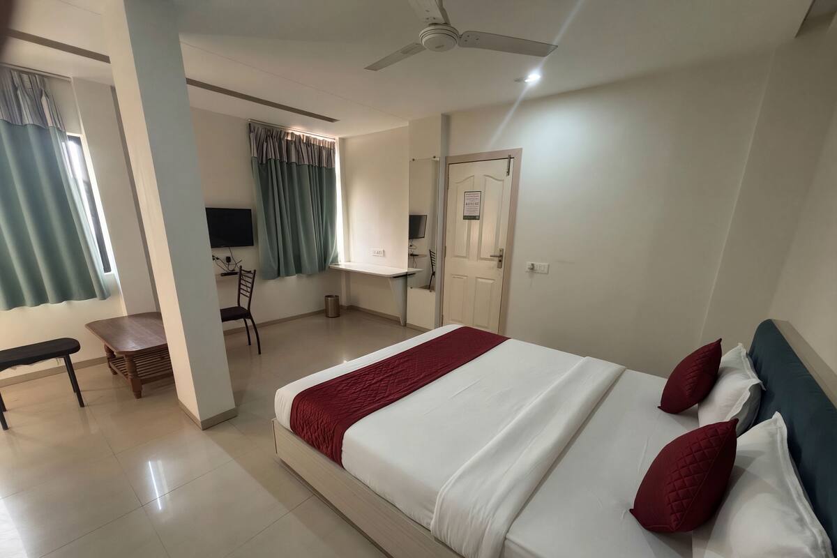 A hotel room with a bed, a desk, a chair, and a TV.