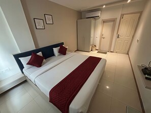 Une chambre d’hôtel comprenant un lit, une armoire, un appareil de climatisation et une porte.