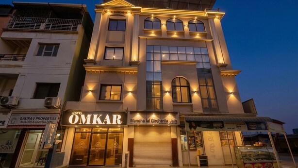A multi-story hotel with a prominent 'OMKAR' sign, large windows, and a well-lit facade. - Shree Omkar Hotel (Indore)