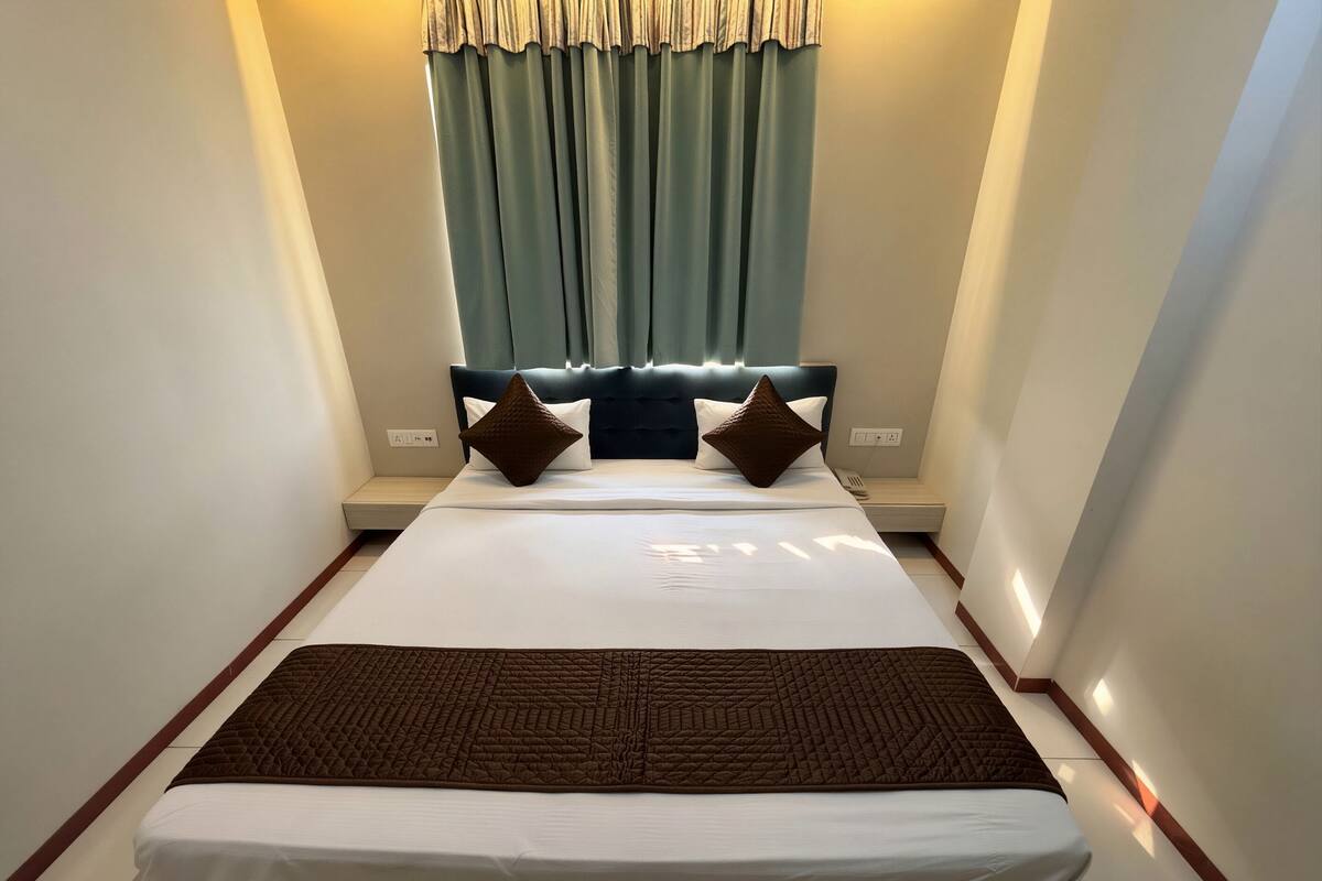 A neatly made bed with a quilted brown blanket, a headboard with a tufted design, and a pair of pillows.