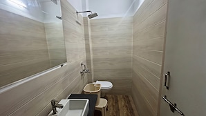 A compact bathroom with a sink, toilet, and shower. - Shree Omkar Hotel (Indore)