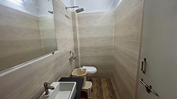 A compact bathroom with a sink, toilet, and shower.