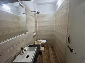 Un baño pequeño con lavamanos, inodoro y ducha.