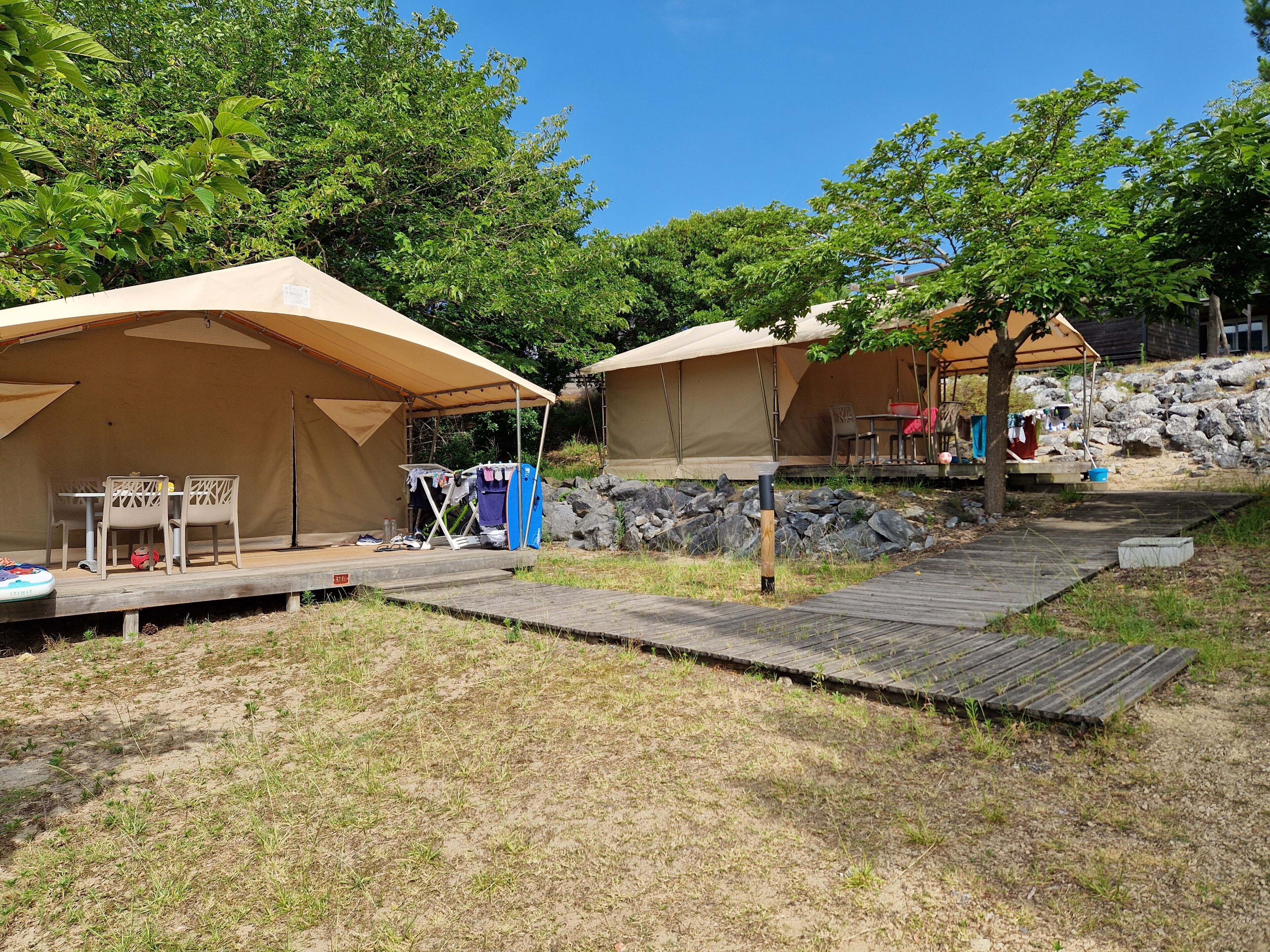 Un camping con tiendas de campaña, una mesa con sillas y una terraza de madera.