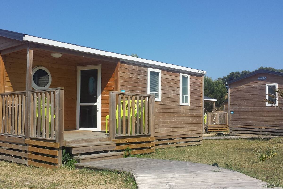 Une cabane en bois avec une véranda, une porte et des fenêtres.