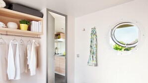 Ein Schlafzimmer mit Bett, Kleiderschrank mit Kleidung, einem Fenster mit Blick und einem Regal.