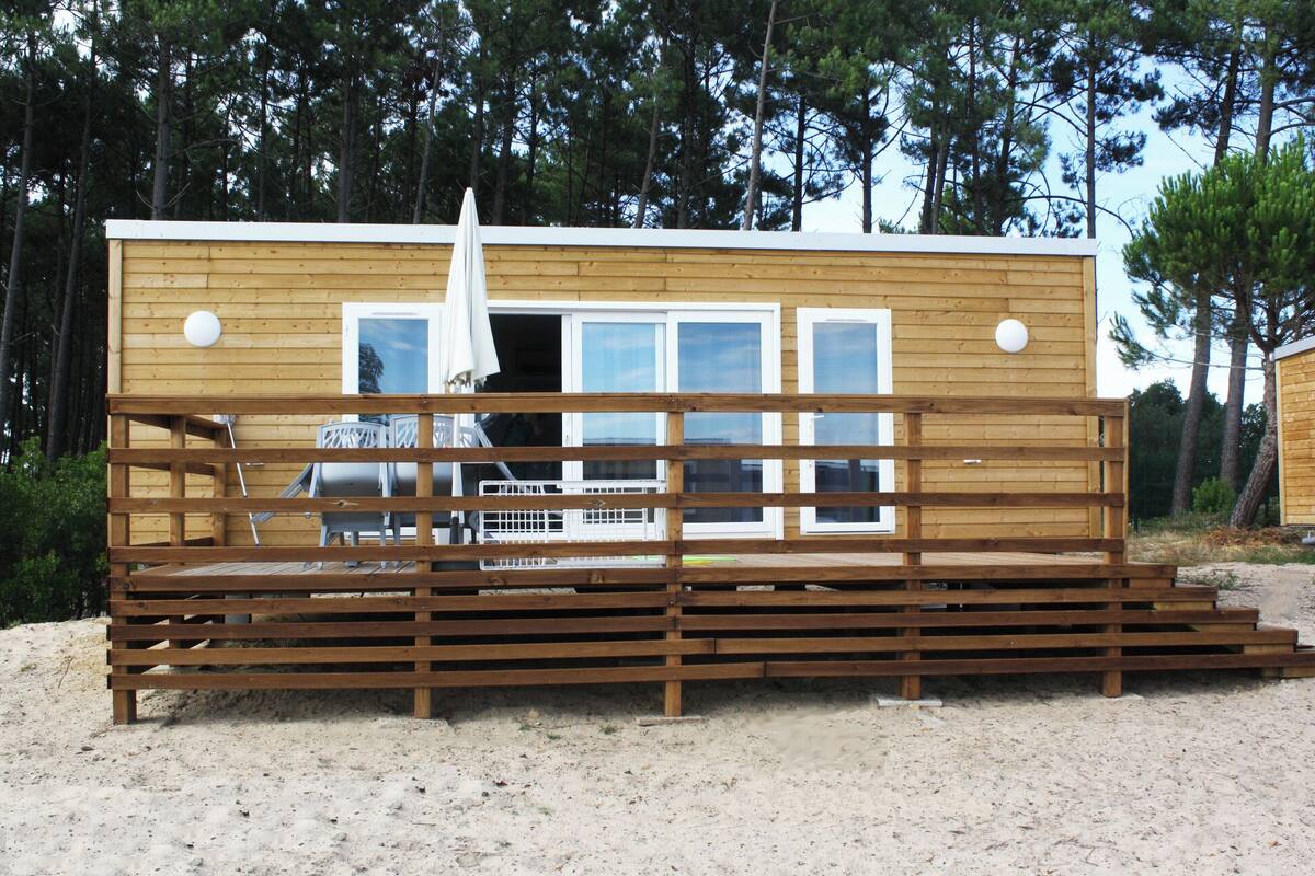 Une cabane en bois dotée d’une terrasse, de fenêtres et d’une porte.