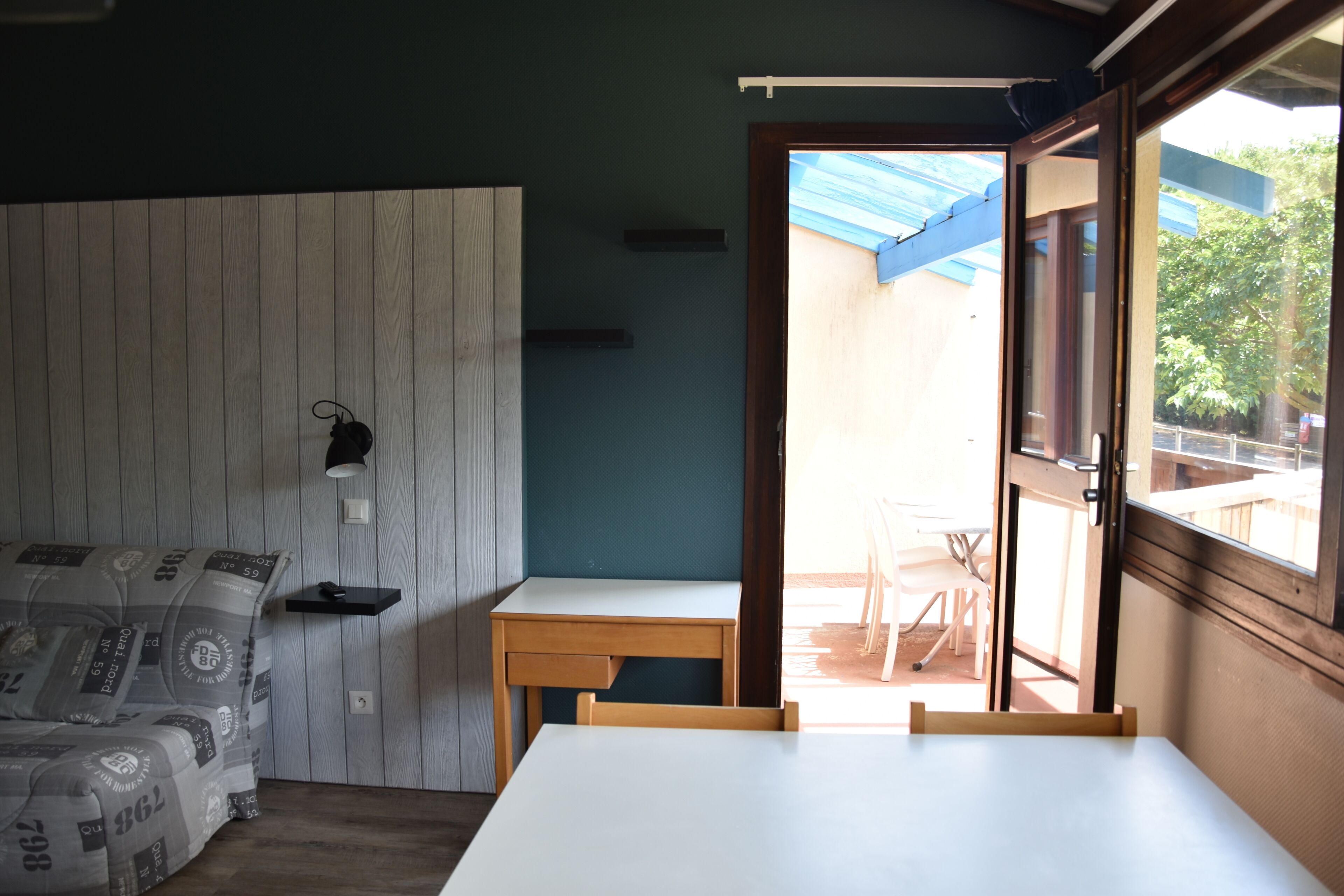 Een kamer met een bed, een bureau, een stoel en een raam.