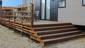 Ein modernes Gebäude mit einer Holzterrasse, Sitzgelegenheiten im Freien und einer Schiebetür.