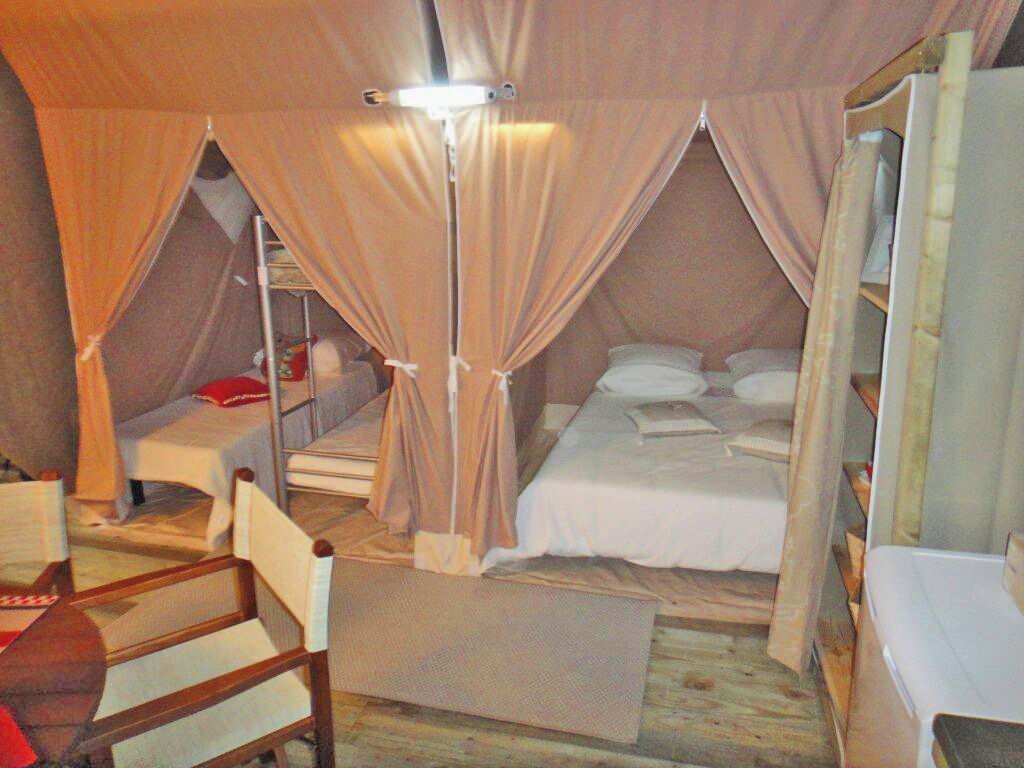 Ein Zeltraum mit einem Bett, einem Sessel, einem Schreibtisch und einer Lampe.