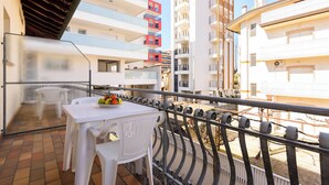 Un balcon avec une table et des chaises, une balustrade et une vue sur les bâtiments voisins.