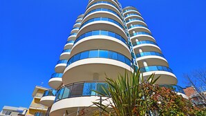 Een hotel met meerdere verdiepingen, een gebogen gevel, balkons en grote ramen.