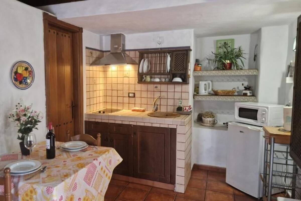 A compact kitchen with a dining area, featuring a tiled backsplash, a microwave, and a small refrigerator.