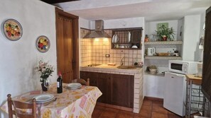 Una cocina compacta con comedor, que presenta un salpicadero de azulejos, un microondas y un refrigerador pequeño.