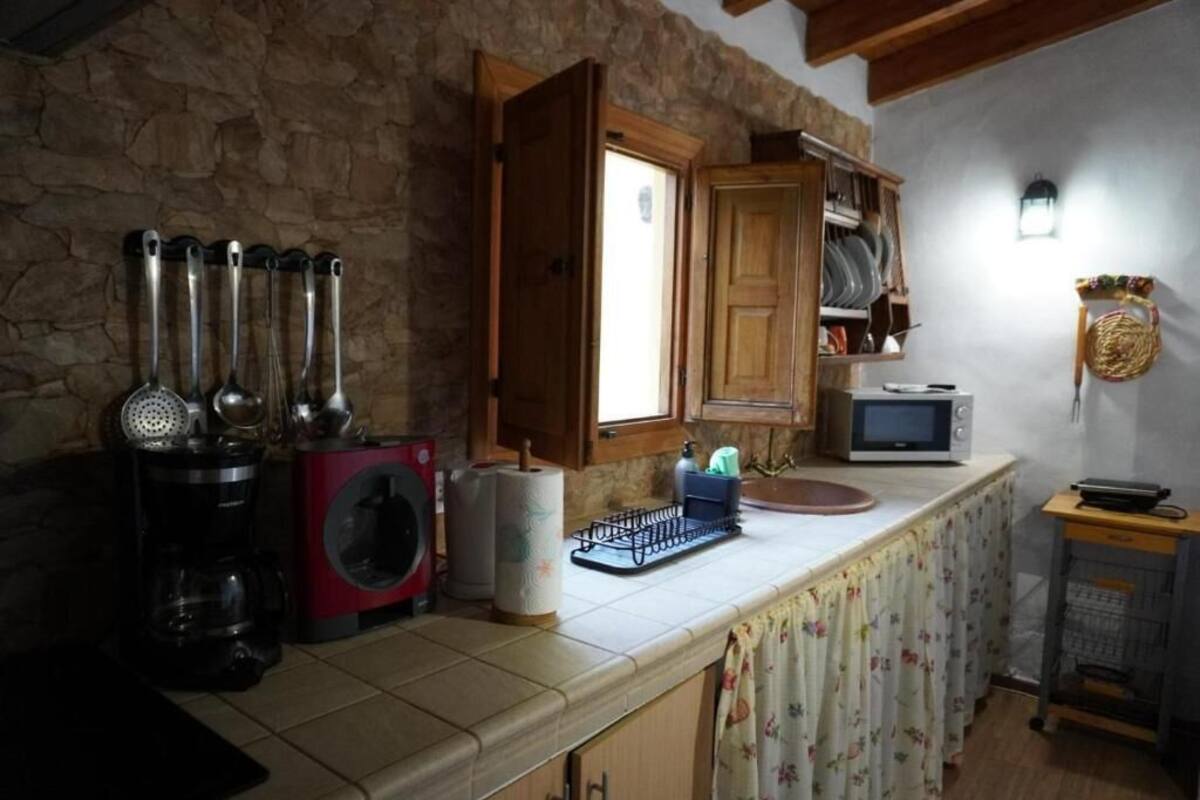 A kitchen with stone walls, a wooden cabinet, a microwave, and a coffee maker.