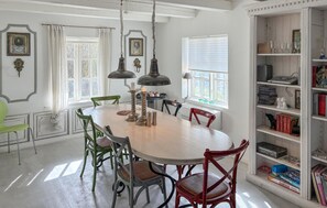 A dining area with a round table, chairs, a chandelier, and a bookshelf with books and decorative items. - 2 bedroom cozy home in Væggerløse (Væggerløse)