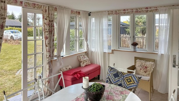 A cozy room with a red sofa, a round table with a candle, and a wicker basket. - 2 bedroom cozy home in Væggerløse (Væggerløse)