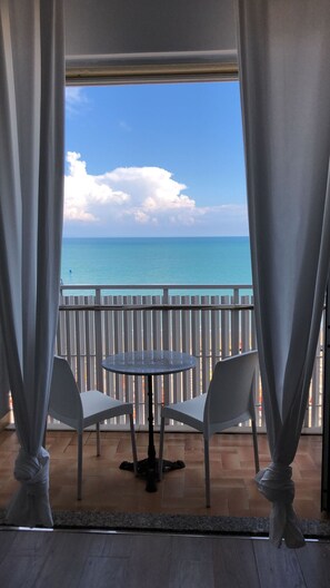 Un balcon avec une table et des chaises, donnant sur une étendue d’eau.