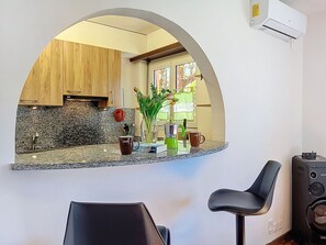 A kitchen with a granite countertop, wooden cabinets, a coffee maker, and a green plant.