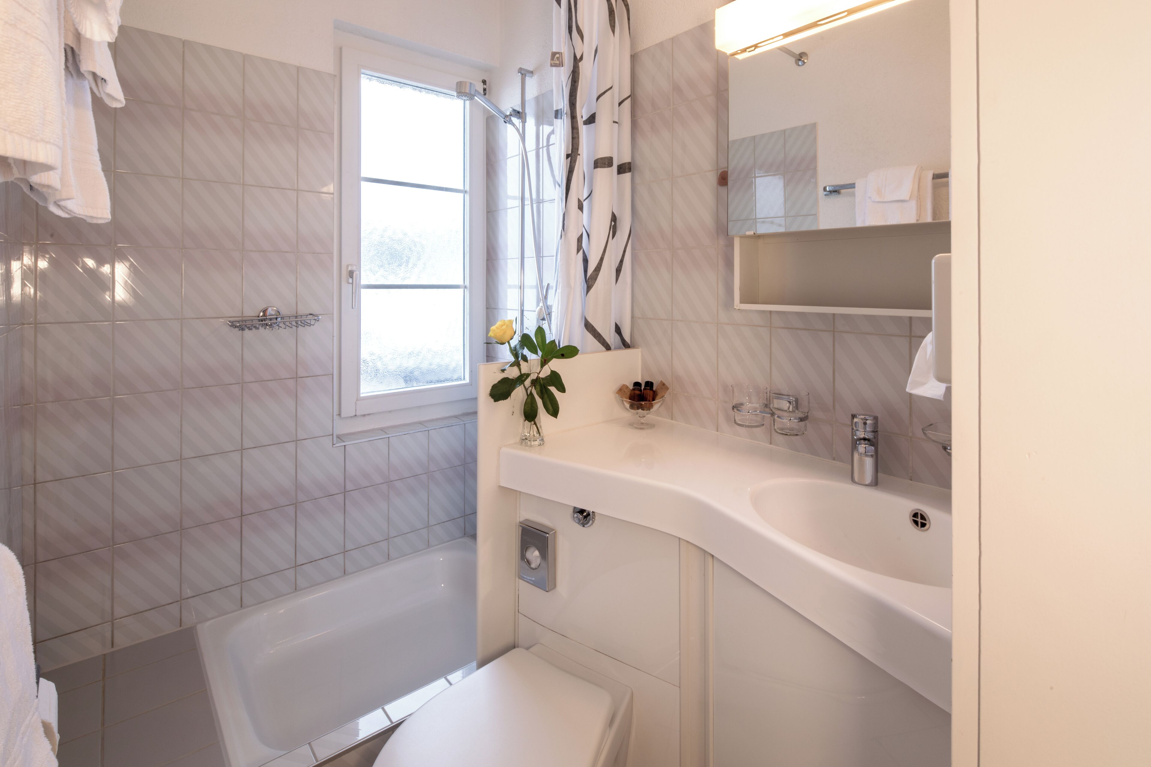 Un baño moderno con una bañera, un inodoro, un lavabo y una ventana.