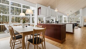 Eine moderne Küche mit großen Fenstern, einem Holzespeisetisch und Stühlen.