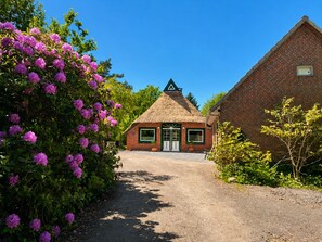 A rustic building with a thatched roof, a brick structure, and a gravel path leading to it. - Vacation home Heilhecker with idyllic garden for families and those seeking peace and quiet (Brake)