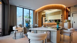 Una cocina moderna con una isla de diseño curvo, un comedor con sillas cómodas y vistas a la ciudad a través de amplios ventanales.