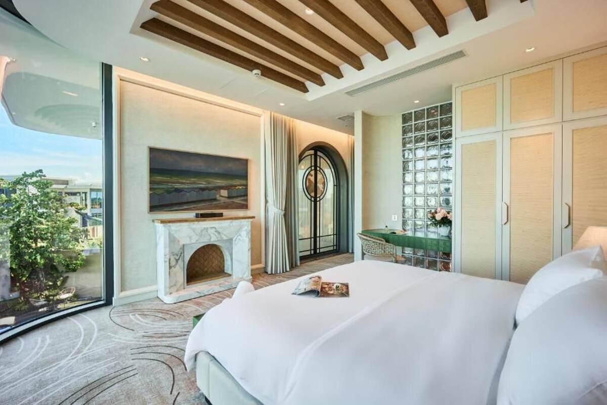 Habitación de hotel moderna con una cama grande, chimenea, vistas a la ciudad y un muro de cristal.