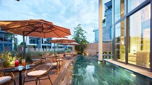 Zona de piscina con mobiliario exterior y sombrillas.