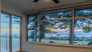 A room with large windows, a view of trees and a road, and a tiled floor.