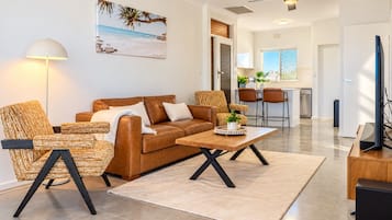 A modern living room with a brown leather sofa, a woven armchair, and a wooden coffee table.