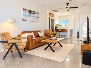 A modern living room with a brown leather sofa, a woven armchair, and a wooden coffee table.