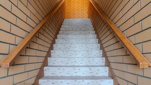 A staircase with a brick wall on either side and wooden handrails.