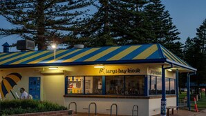 A kiosk named 'Largo Bay Kiosk' with a striped roof, a bench, and a signboard.