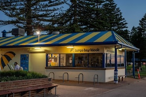Un quiosco llamado 'Largo Bay Kiosk' con techo a rayas, una banca y un letrero.