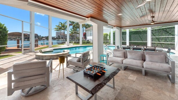 A spacious outdoor lounge area with a pool, seating, and a view of the water. - Upscale Canal Home w/ Heated Pool & Spa (Marco Island)