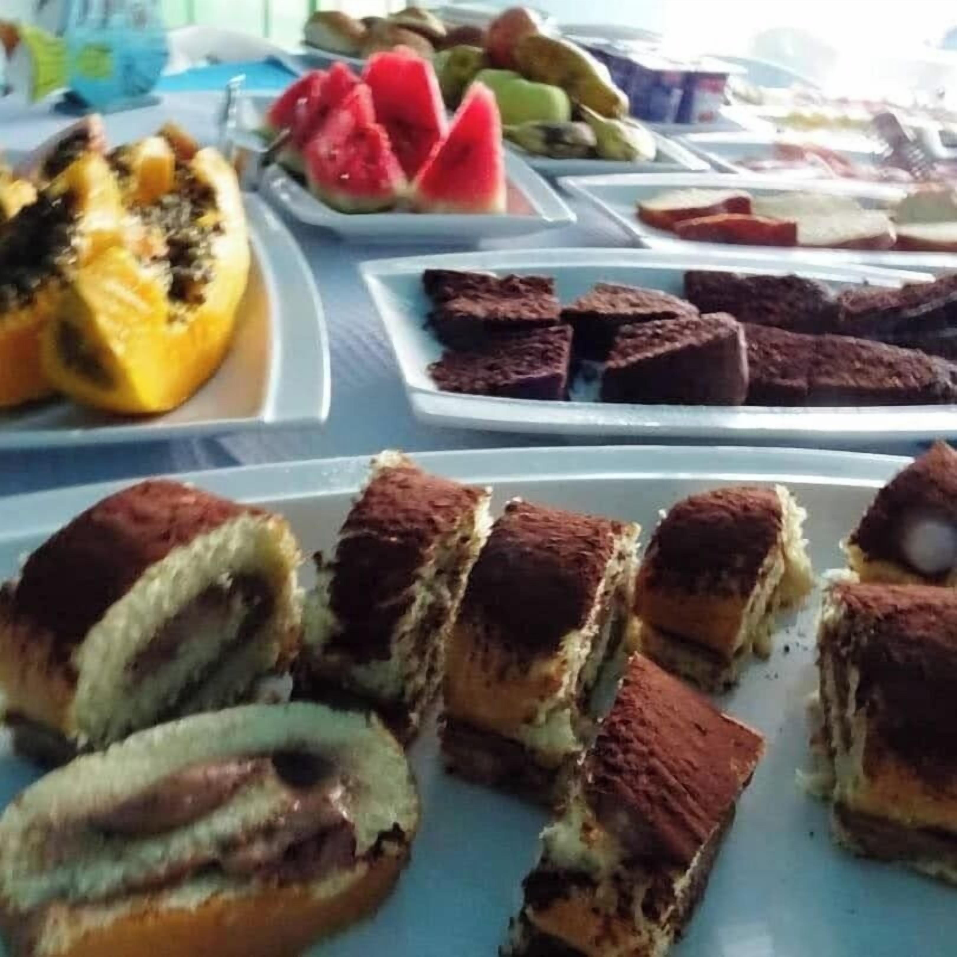 Een buffettafel met diverse gerechten, waaronder gevulde paprikas, fruit en desserts.