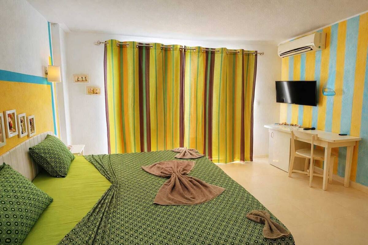 A hotel room with a bed, a desk, a TV, and a curtain.