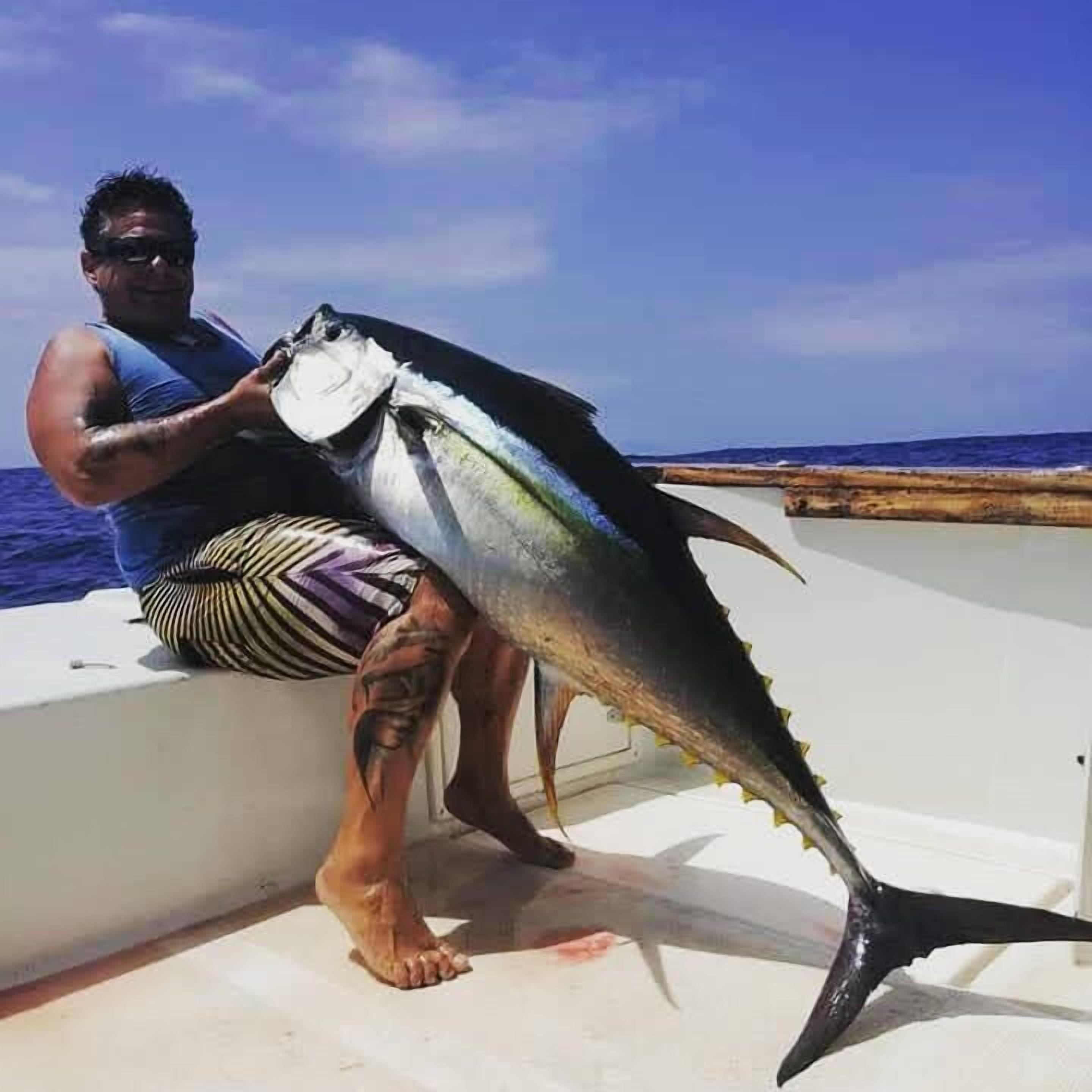 A person holding a large fish on a boat.