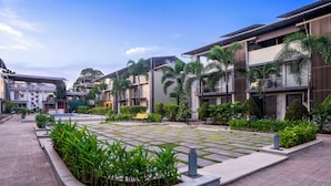 A courtyard with a central water feature, surrounded by modern buildings with balconies and greenery. - Alaya Stays Rosalia 3BHK Villa with Pool (Lonavala)