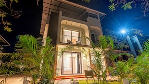 A modern two-story building with large windows, a balcony, and a well-lit entrance. - Alaya Stays Rosalia 3BHK Villa with Pool (Lonavala)