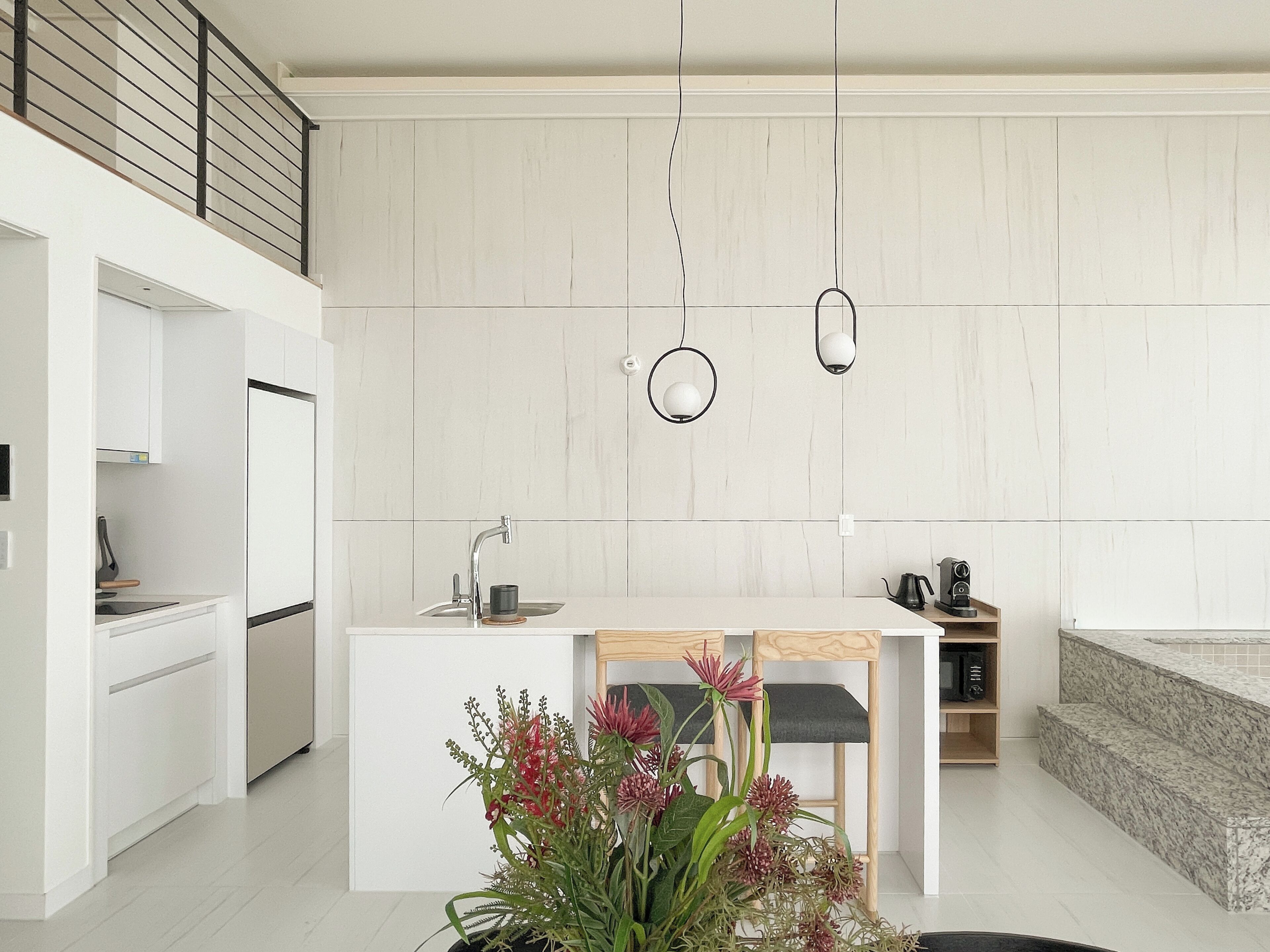 A modern kitchen with a built-in island, white cabinetry, and pendant lighting.