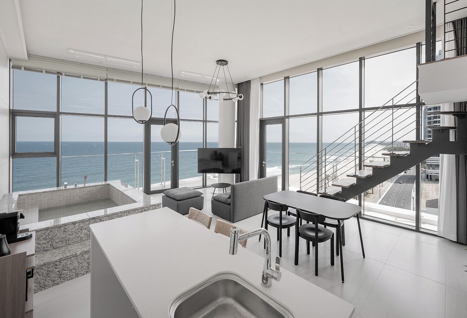 A modern kitchen with a large island, dining area, and a view of the ocean.