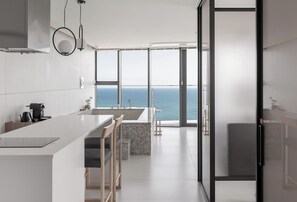 A modern kitchen with a large island, a view of the sea, and a glass door leading to a balcony. - Plott The Gak Yangyang (Yangyang)